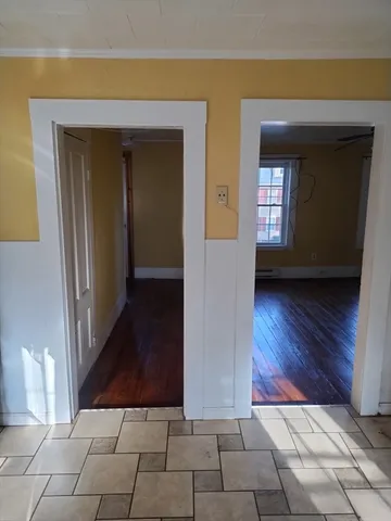 a view of a hallway with wooden floor and a living room