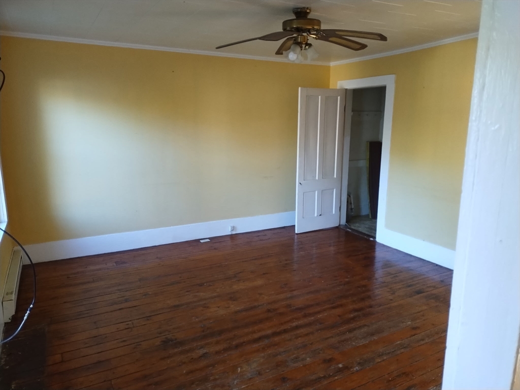 429 Main Street, Unit 429 Hardwick, MA 01031 - Photo 4 of 10 an empty room with wooden floor chandelier fan and closet area