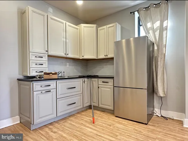 a kitchen with stainless steel appliances granite countertop a refrigerator sink and white cabinets