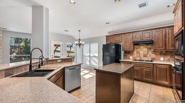 a large kitchen with stainless steel appliances lots of counter top space and windows