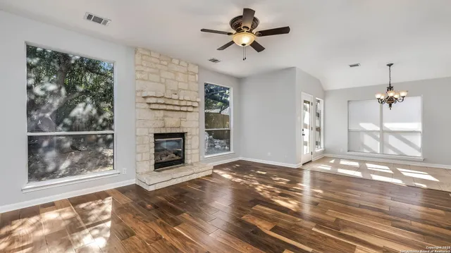 a view of a livingroom with a fireplace a ceiling fan and windows