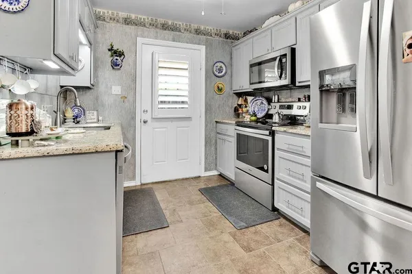 a kitchen with stainless steel appliances granite countertop a stove a sink and a refrigerator