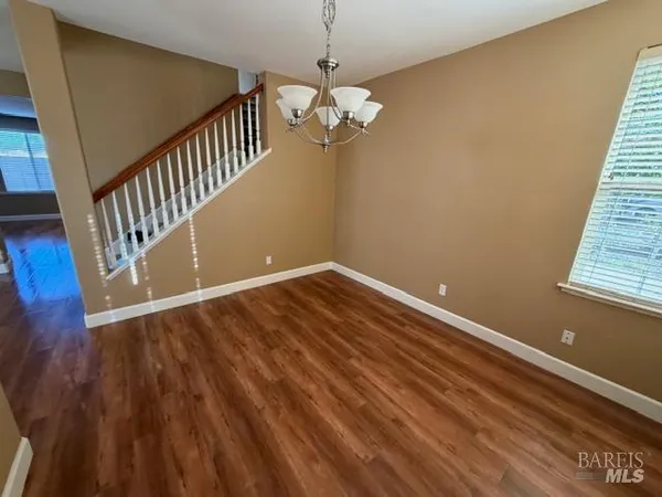 an empty room with a chandelier fan and a window