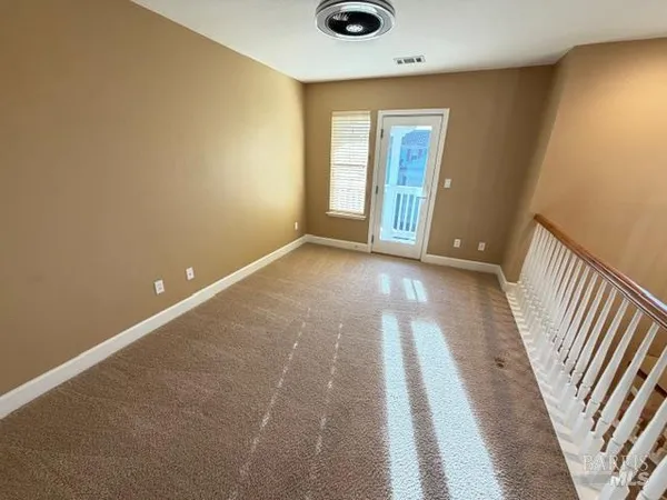 an empty room with a chandelier fan and windows