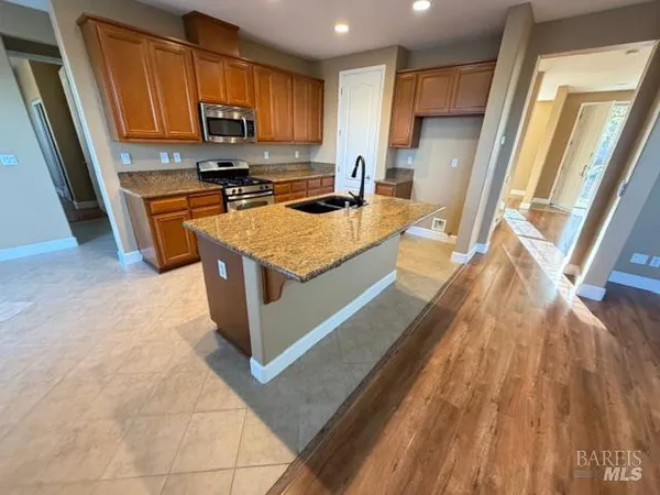a kitchen with stainless steel appliances granite countertop a stove a sink and a microwave