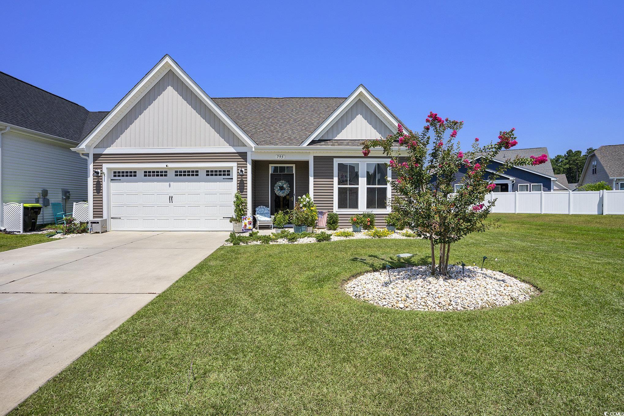 View of front of home with an attached garage, driveway, roof with shingles, and board and batten siding