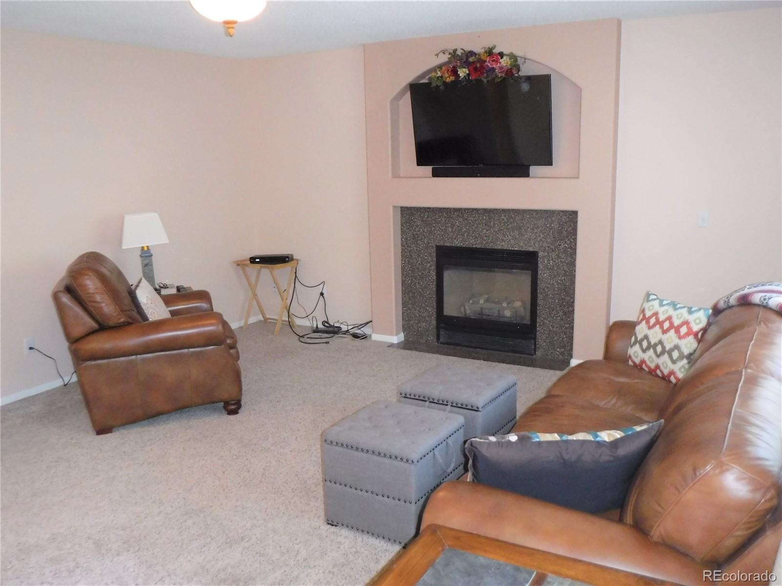 1149 Timbervale Trail Highlands Ranch, CO 80129 - Photo 17 of 32 a living room with furniture a flat screen tv and a fireplace