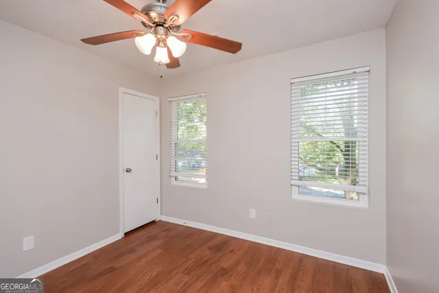 a view of an empty room with a window and wooden floor