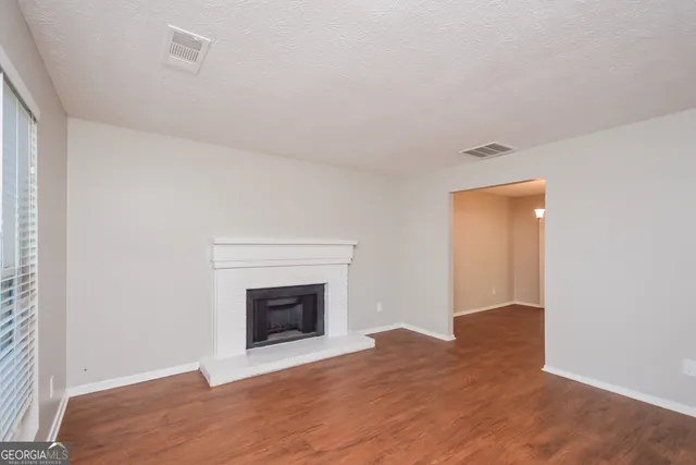 a view of empty room with wooden floor and fireplace