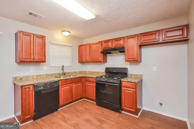 a kitchen with stainless steel appliances granite countertop a stove sink and cabinets