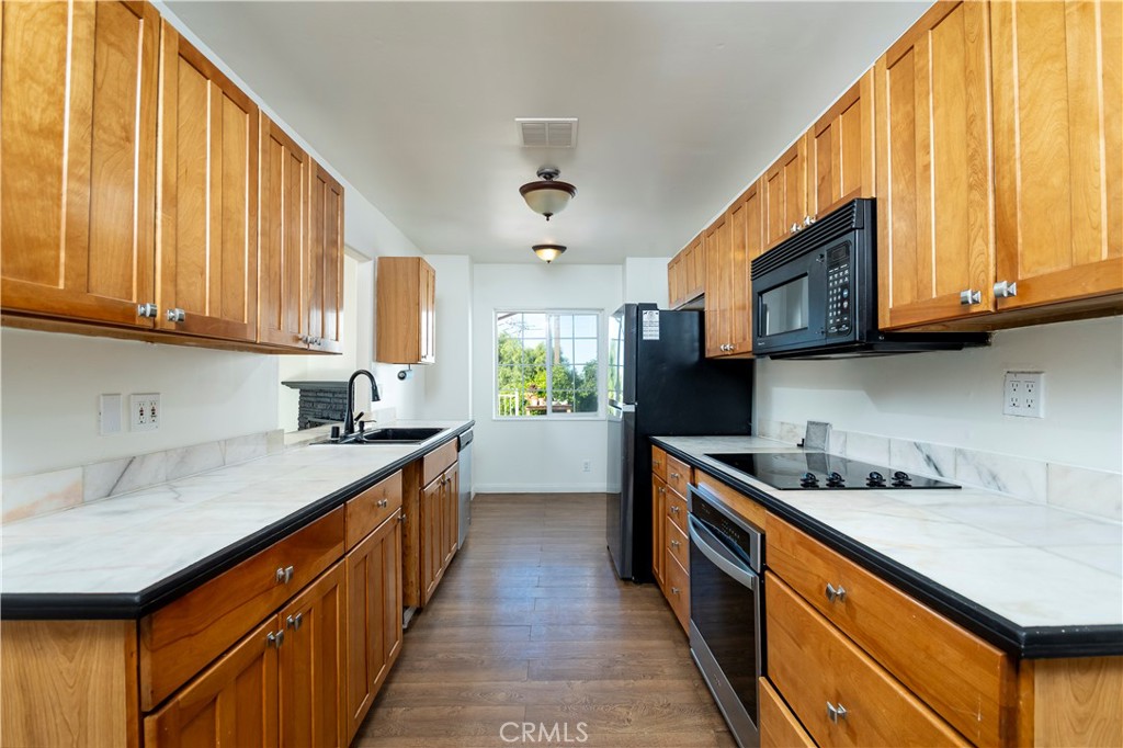 10161 Foothill Boulevard Sylmar, CA 91342 - Photo 11 of 65 a kitchen with stainless steel appliances granite countertop a sink a stove and a wooden cabinets