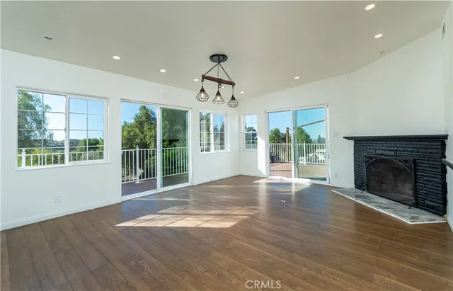 a view of an empty room with wooden floor fireplace and a window