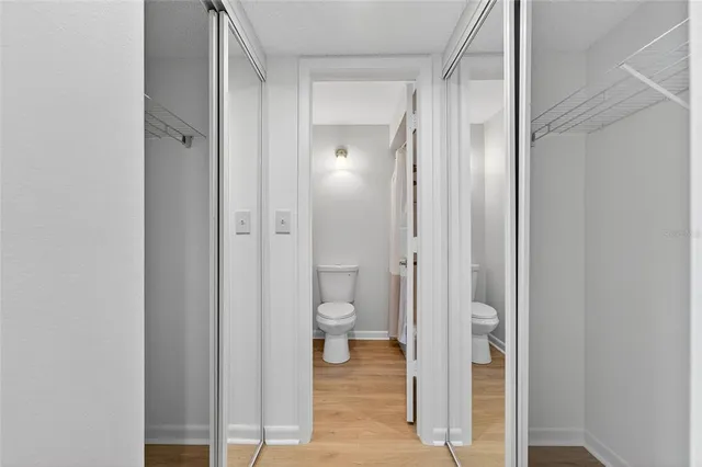 a view of an empty room with wooden floor & closet