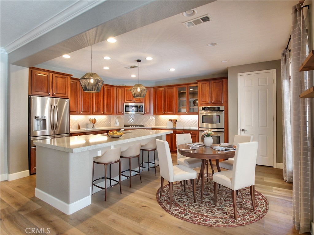 1442 Midnight Sun Drive Beaumont, CA 92223 - Photo 15 of 46 a kitchen with stainless steel appliances kitchen island granite countertop a dining table chairs and granite counter tops