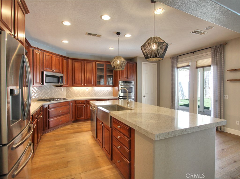 1442 Midnight Sun Drive Beaumont, CA 92223 - Photo 18 of 46 a large kitchen with a large counter top space a sink stainless steel appliances and cabinets