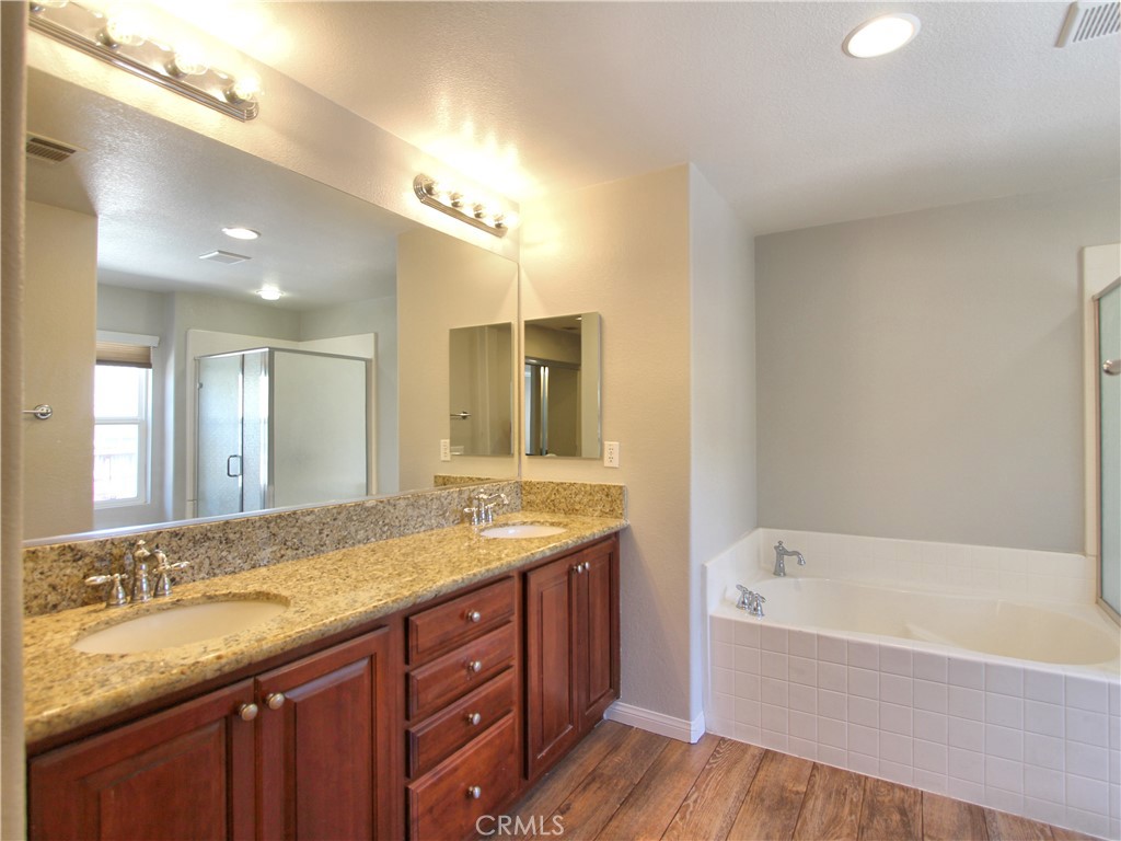 1442 Midnight Sun Drive Beaumont, CA 92223 - Photo 36 of 46 a bathroom with a granite countertop bathtub a sink and a large mirror