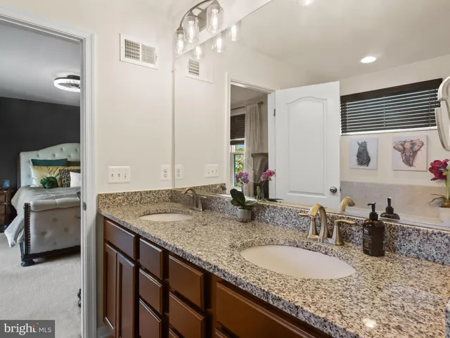 a bathroom with a granite countertop double vanity sink and mirror