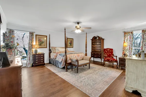 a bedroom with a bed a dresser and painting on the wall
