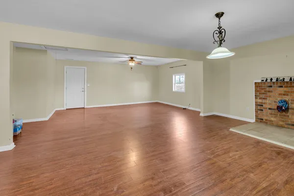 a view of an empty room with window and wooden floor