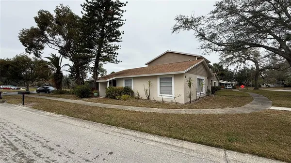 a view of a house with a yard and large trees