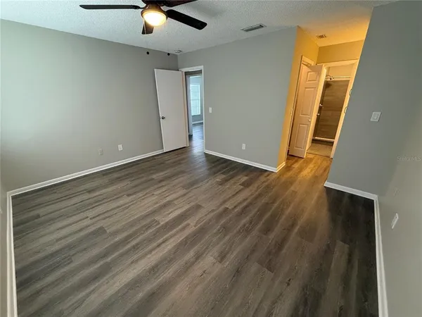 an empty room with wooden floor and chandelier fan