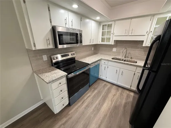 a kitchen with granite countertop a sink a stove a microwave and wooden cabinets