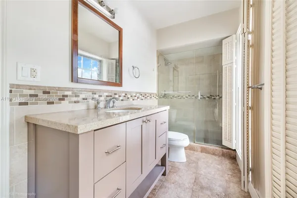 a bathroom with a granite countertop sink a toilet and a mirror