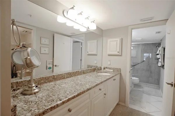 a bathroom with a granite countertop sink a mirror and shower