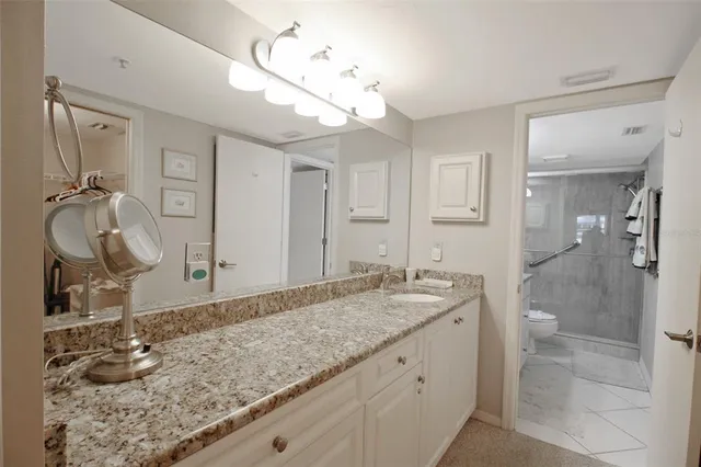 a bathroom with a granite countertop sink a mirror and shower