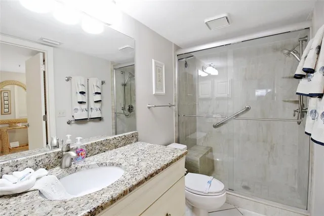 a bathroom with a granite countertop sink toilet a mirror and shower