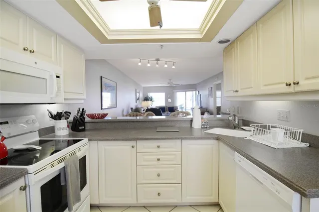 a kitchen with a sink dishwasher a stove and white cabinets with wooden floor