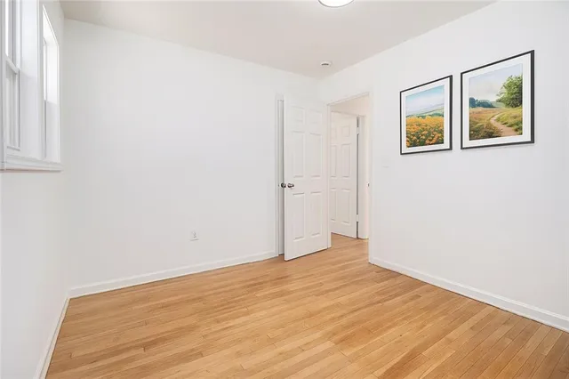 an empty room with wooden floor and window