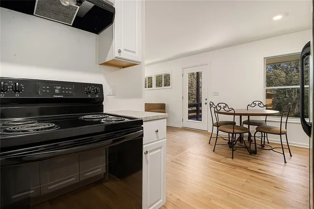 a kitchen with a stove a microwave and a dining table with wooden floor