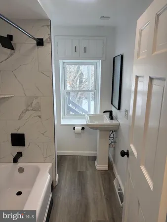 a bathroom with a tub a sink and glass windows