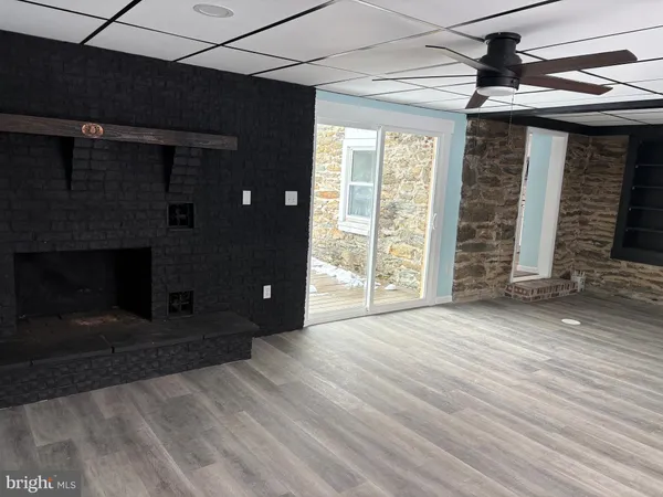 a view of an empty room with wooden floor and a fireplace