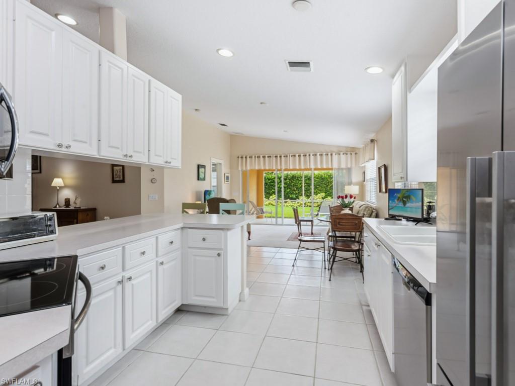 7520 Firenze Lane Naples, FL 34114 - Photo 11 of 32 a kitchen with white cabinets and white appliances