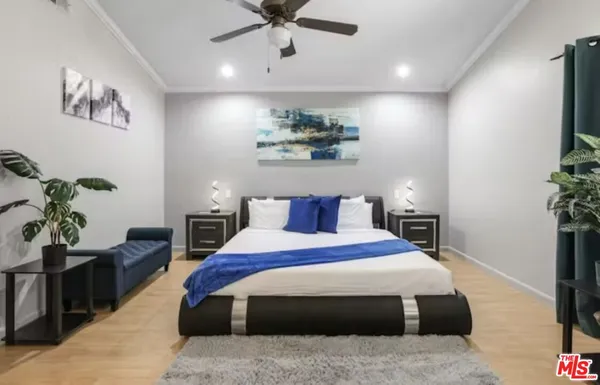 a bedroom with a bed potted plant with the wooden floor
