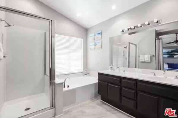 a bathroom with double vanity sinks a large mirror and a bathtub
