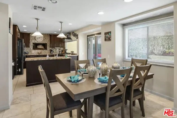 a dining room with stainless steel appliances kitchen island granite countertop a dining table chairs and a oven