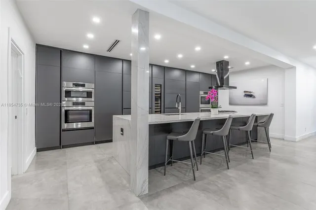 a kitchen with kitchen island a white cabinets and chairs