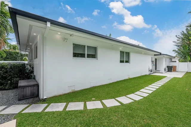a view of a house with a yard and palm trees