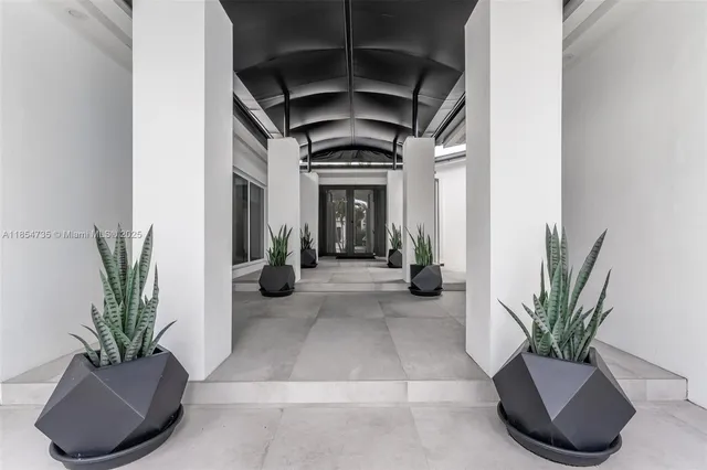 a view of a white house with a large tree and wooden fence