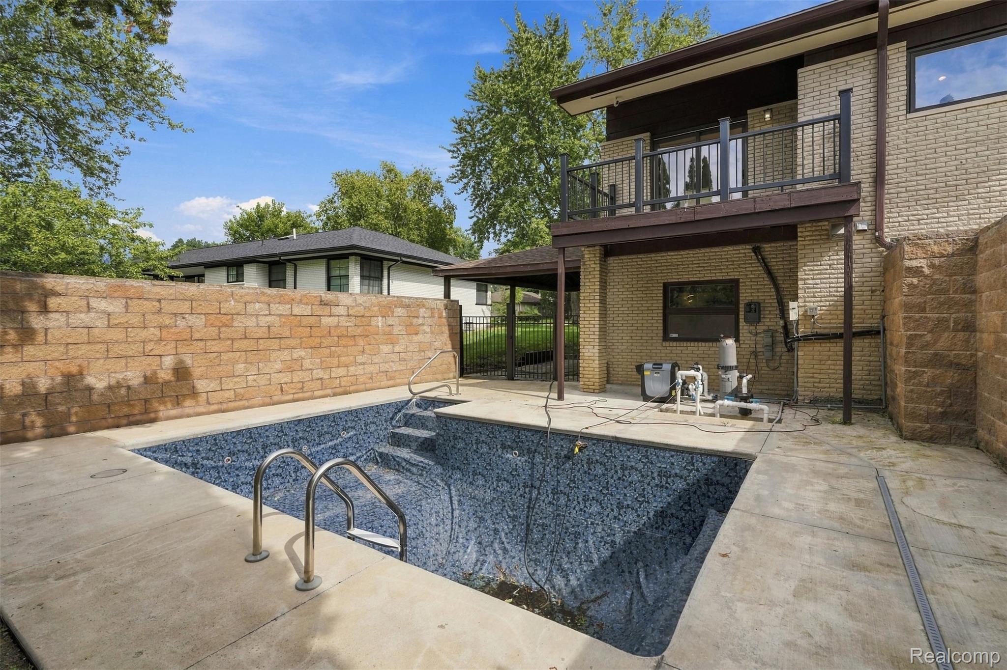 27507 Bell Road Southfield, MI 48034 - Photo 57 of 81 Concrete patio surrounding a rectangular swimming pool with integrated steps and a mosaic-patterned interior