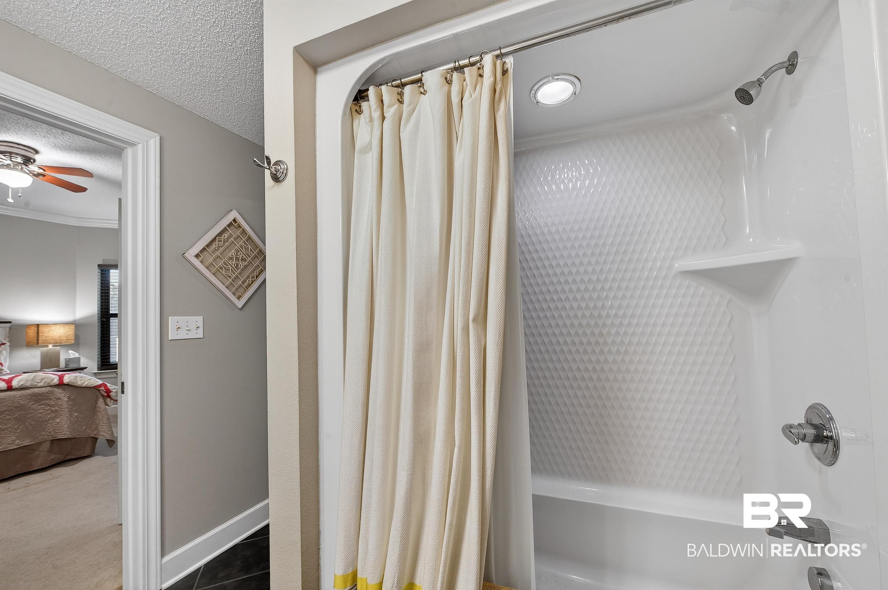 27582 Canal Road, Unit 2507 Orange Beach, AL 36561 - Photo 42 of 75 Ensuite bathroom with shower / bath combination with curtain, a textured ceiling, and dark colored carpet