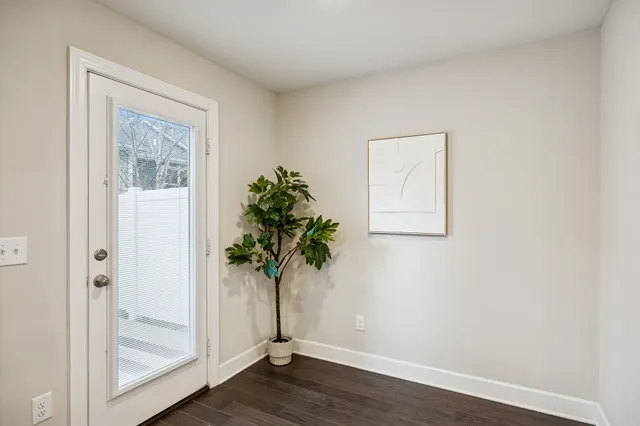 an empty room with wooden floor and a potted plant