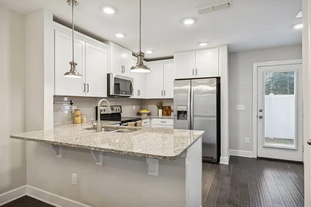 a kitchen with stainless steel appliances granite countertop a refrigerator a sink a stove and a refrigerator