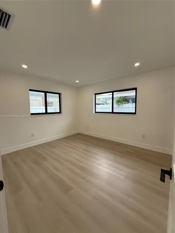 a view of a big room with wooden floor and windows