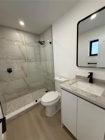a bathroom with a granite countertop sink toilet and shower