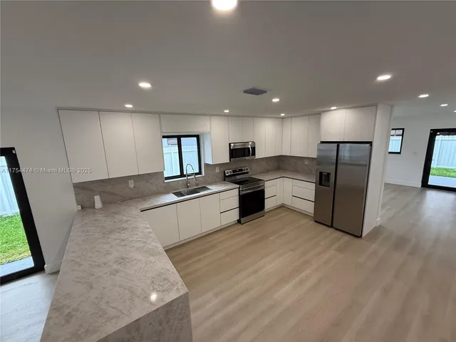 a large kitchen with a lot of counter top space stainless steel appliances and a window