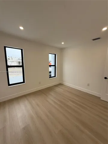 a view of an empty room with window and wooden floor